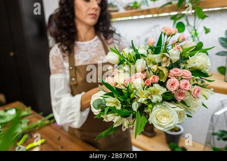 Attractive young woman florist is working in a flower shop.