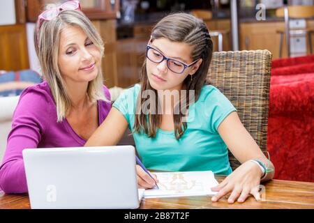 pretty teen girl doing homework with her mother Stock Photo