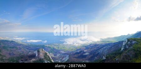 View of the huge rocky cliffs and green valley covered with forest. Beautiful mountain landscape Stock Photo