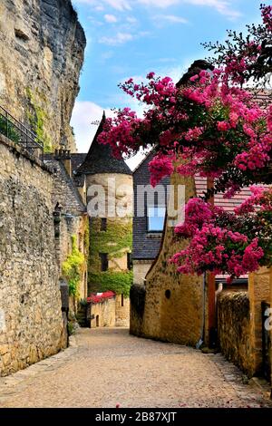 Beautiful village street with flowers and medieval tower, Dordogne, France Stock Photo