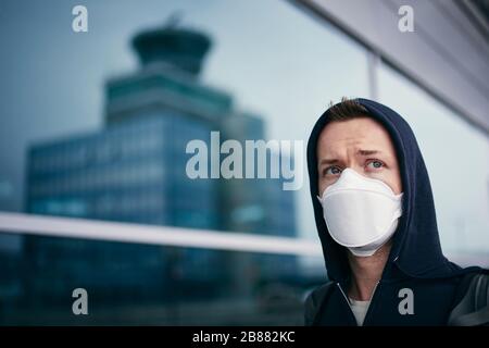 Young tourist wearing face mask against reflection airport terminal building. Themes coronavirus, travel and personal protection. Stock Photo