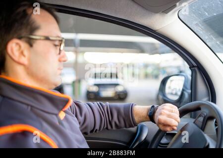 Delivery man driving a car and looking on the watch, Poland Stock Photo