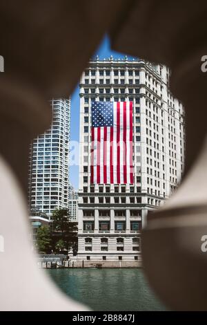large american flag of united states of america hanging on the side of a building in the urban city to celebrate Independence Day on the fourth of Jul Stock Photo