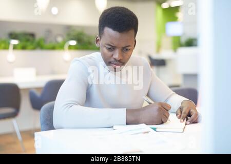 Portrait of young African-American man using laptop at work, copy space Stock Photo
