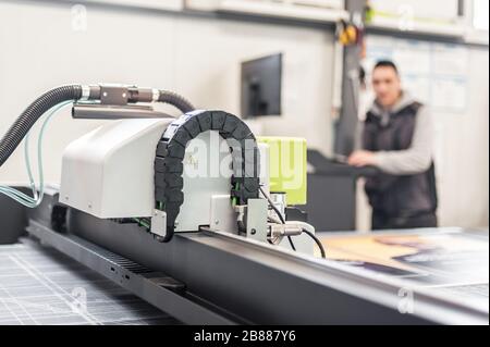 Printshop worker technician works on large CNC computer numerical control printing and cutting machine Stock Photo