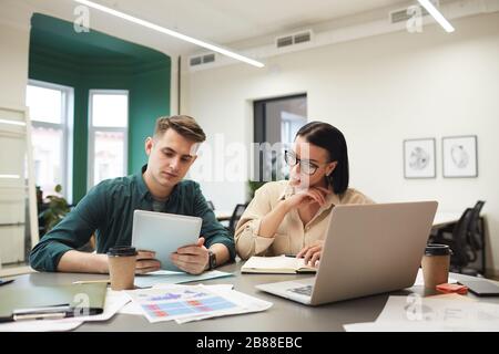 Young business people using tablet pc and laptop while working over new project in team at meeting Stock Photo