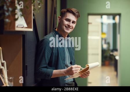 Portrait of young man smiling at camera while standing and examining contract in his hands Stock Photo
