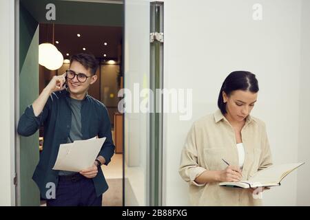Two office worker busy with their work they talking on the phone and working with documents at office Stock Photo