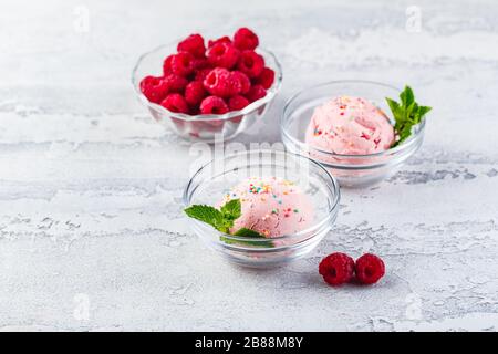 Raspberry ice cream balls with berries and mint leaves in glass bowls Stock Photo