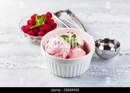 Raspberry ice cream balls with berries and mint leaves in white bowl Stock Photo
