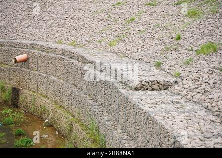 the edge of the city stream, made of stones in an iron grid. nobody Stock Photo