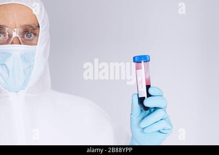 Scientist in protective suit holding test tube with blood Stock Photo
