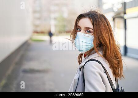 Young woman with beautiful blue eyes and disheveled hair wearing protection face mask against coronavirus MERS-Cov, Novel coronavirus 2019-nCoV Stock Photo