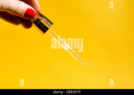 Pipette with gualinic liquid in a female hand. Serum with gold particles for the skin. Copy space for text Stock Photo