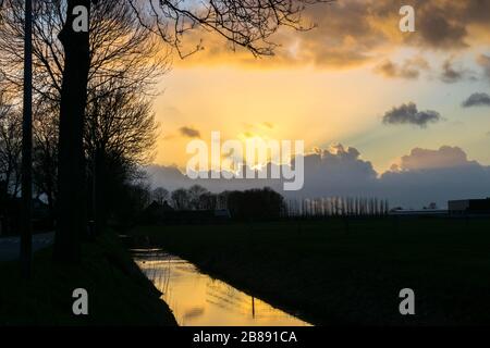 Sun beams shine from behind cumulus clouds in the distance Stock Photo