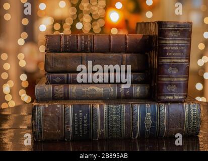 A vintage pile of three old brown leather books with eye glasses on a wood table. Stock Photo
