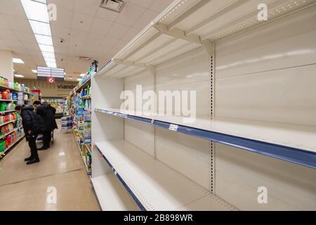 Montreal, CA - 20 March 2020: Empty shelves of toilet paper in a supermarket. Shortage of supplies due to panic of Coronavirus. Stock Photo