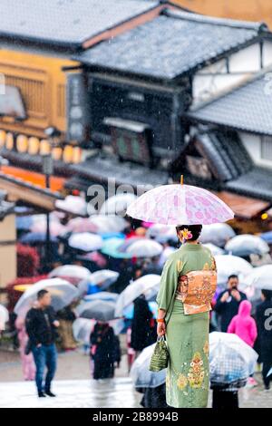 Many people with umbrellas and kimono costume during rainy day by street near Kiyomizu-dera temple in Kyoto, Japan Stock Photo