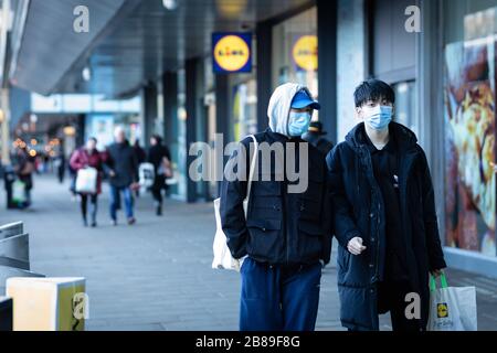 Manchester, UK. 20 March, 2020. UK. Members of the public wearing masks walk through Piccadilly during Friday lunchtime. Credit: Andy Barton/Alamy Live News Stock Photo