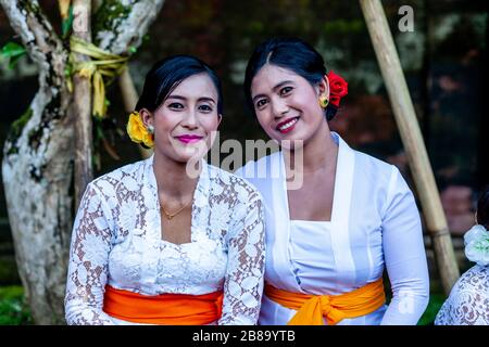 Two Balinese Women In Traditional Dress Pose For A photo At A Hindu Festival, Tirta Empul Water Temple, Bali, Indonesia. Stock Photo