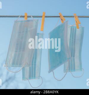 Blue medical face masks hang on a rope with clothespins against the sky Stock Photo