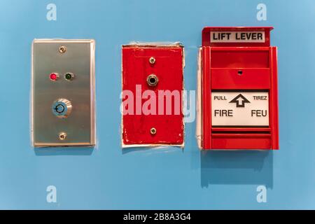 Fire alarm switch button emergency on blue wall texture background. Select focus Stock Photo