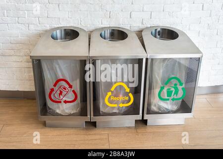 three modern waste bins Silver color for e-waste, recycle, general waste with red, yellow and green symbols Stock Photo