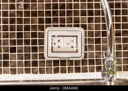 Power plug socket with waterproof protection or outlet cover, plug housing on wall tiles In the kitchen room Stock Photo
