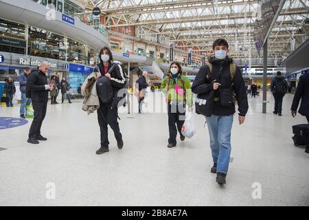 London, UK. 20th Mar, 2020. Commuters with face masks walk through the Waterloo Station, one of London's busiest train stations, in London, Britain on March 20, 2020. Cafes, bars, pubs and restaurants must close from Friday night across Britain in a bid to contain the spread of COVID-19 outbreak, Prime Minister Boris Johnson said Friday. As of 9 a.m. local time (0900 GMT) Friday, the number of confirmed COVID-19 cases in Britain reached 3,983, according to the Department of Health and Social Care. As of 1 p.m. Credit: Xinhua/Alamy Live News Stock Photo