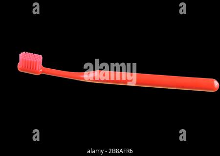 Red toothbrush isolated on the black background. Stock Photo