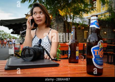 Vietnamese woman doing business on the phone while on vacation in Hoi An, Vietnam Stock Photo