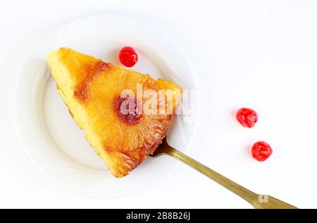 Slice of pineapple upside down cake with glacé cherry isolated on white background.Top view. Homemade baking. Stock Photo