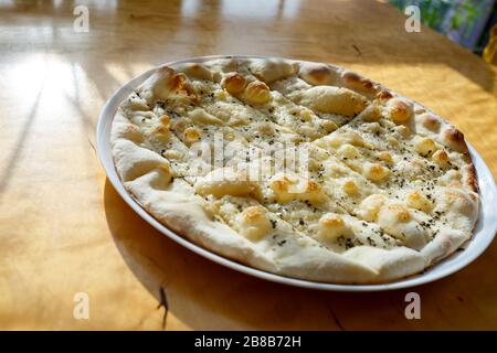 large freshly baked pizza with spices sprinkled with cheese in bright sunlight Stock Photo