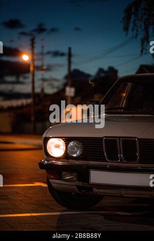 Beautiful shot of a white vintage classic car with round headlights in the street at night Stock Photo