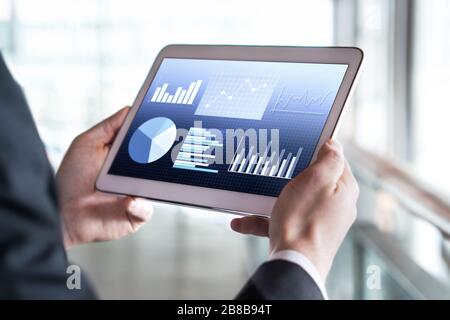 Close up of businessman using tablet in modern office building. Man reading financial statistics, business graphs and trade data. Stock Photo