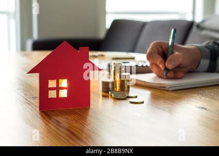 Man counting house price, home insurance cost, property value or rent on paper. Realtor or real estate agent writing offer. Stock Photo