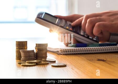 Man using calculator to count money savings and living costs. Inflation, taxes and rising expenses. Calculating daily family groceries price. Stock Photo