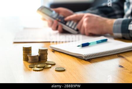 Man planning family finance and using calculator. Counting savings, budget, taxes, expenses and living cost. Calculating money. Accountant working. Stock Photo