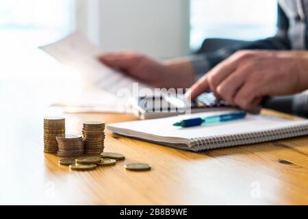 Man using calculator and reading financial document paper. Entrepreneur, bookkeeper or accountant working and counting tax, vat, loan, debt or savings. Stock Photo