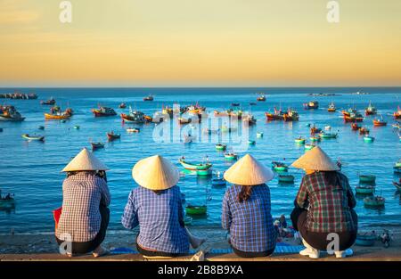 A group of vietnamese women waiting for the fishing boat on the port at dawn morning in a small village close to Mui Ne, Vietnam. Stock Photo