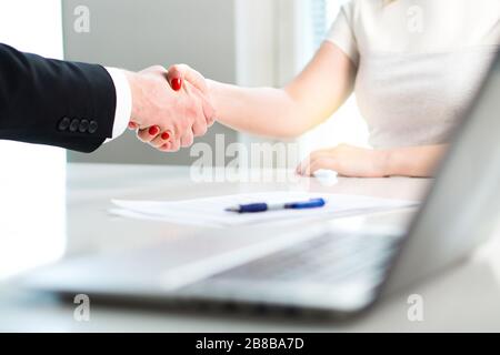 Business man and woman shaking hands after successful job interview or meeting. Young applicant making contract of employment. Stock Photo