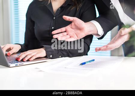 Disappointed or angry boss yelling at employee. Unhappy manager talking to bad assistant or secretary. Businessman spreading hands in office. Stock Photo