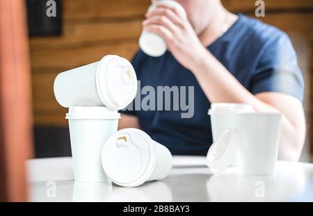 Coffee or caffeine addiction concept. Addicted or thirsty man drinking too much. Addict with many empty take away paper cups on table. Stock Photo
