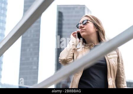 Frustrated woman talking on the phone in the city. Annoyed or serious lady with smartphone having stress. Stock Photo