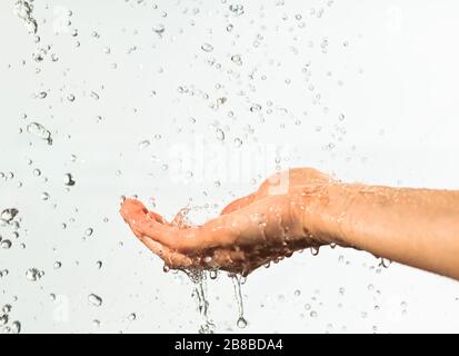 Closeup of drops of water flowing into palm, waters splashes scatter to sides. Photo on white background Stock Photo
