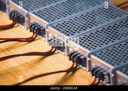 Metal mesh cases of power supply and wires are on a wooden table at the production of high-tech computers. Concept of high technology and industrial p Stock Photo