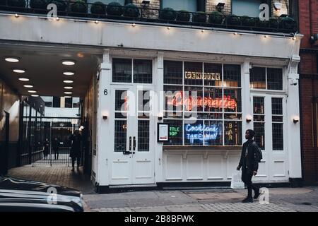 London, UK - March 06, 2020: Facade of Genuine Liquorette bar in Soho, an area of Central London famous for bars, cafes and restaurants, man walking p Stock Photo