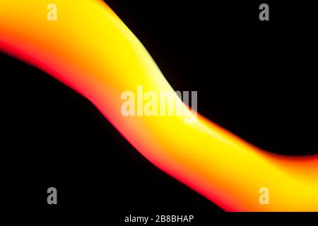 Abstract yellow and orange light painting curving on a black background. Stock Photo