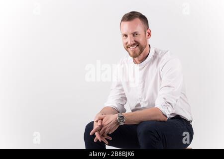 A young handsome male sitting and posing isolated on white background Stock Photo