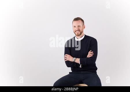 A young handsome male sitting and posing isolated on white background Stock Photo